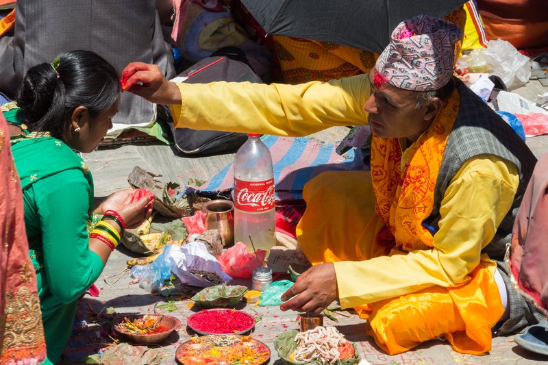 Priest applying Tika on the forehead of a woman (1).jpg